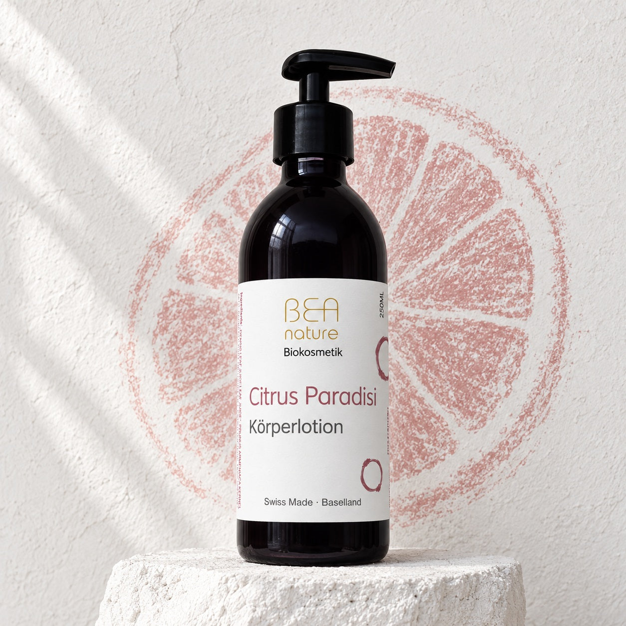 Citrus Paradisi Körperlotion in der 250-ml-Mironglasflasche vor einer Grapefruitzeichnung in Kreide